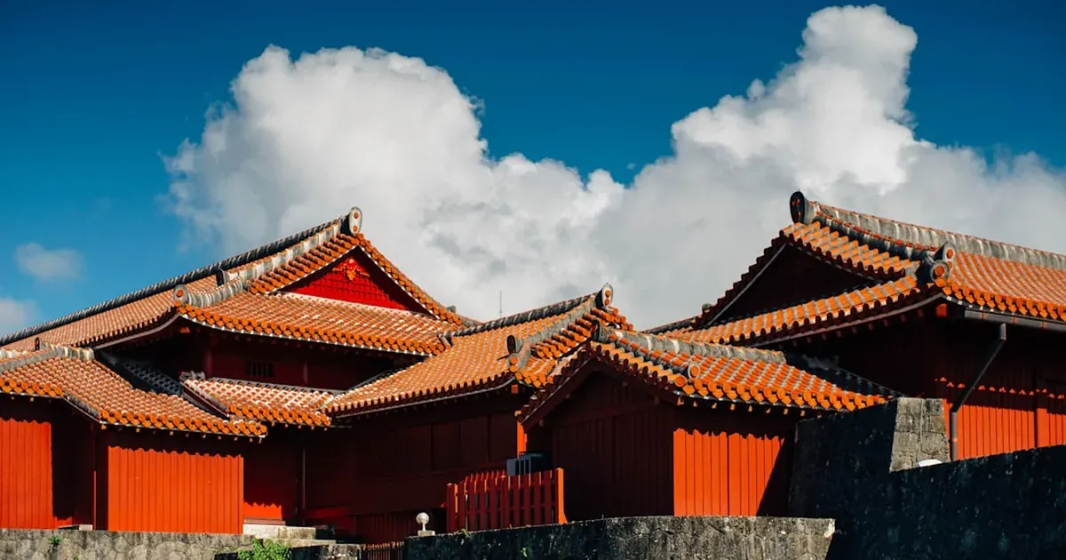 Shuri Castle in Naha Okinawa with distinctive red lacquered walls, golden roof ornaments, and tropical sky in the background