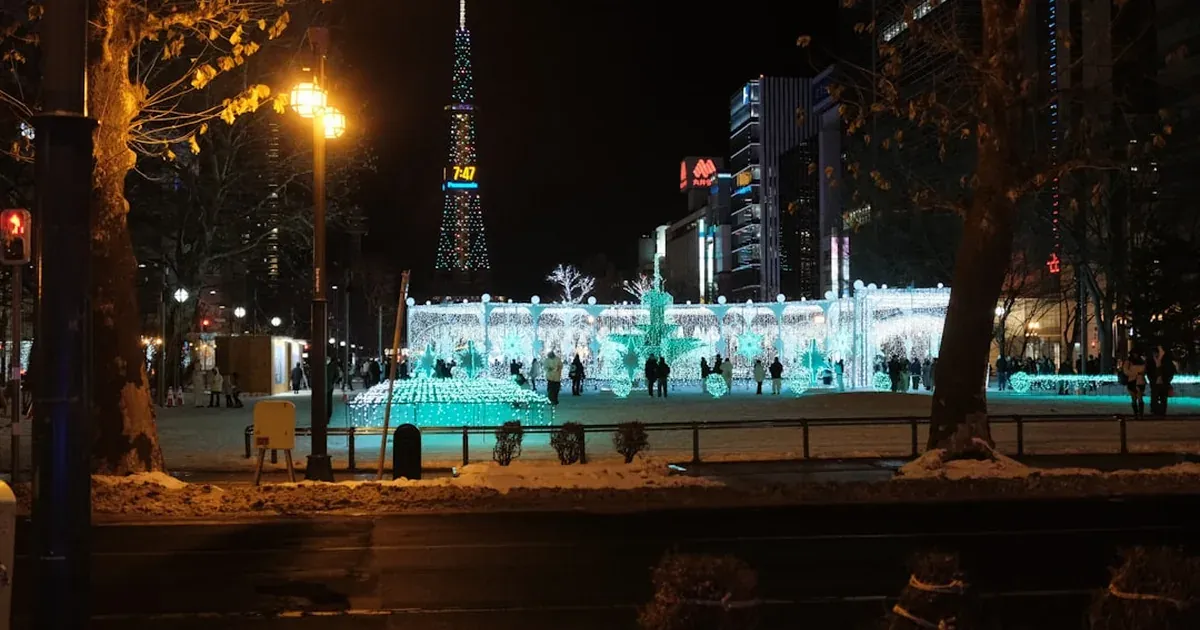 Towering illuminated snow sculptures at the Sapporo Snow Festival in Odori Park at night with crowds viewing