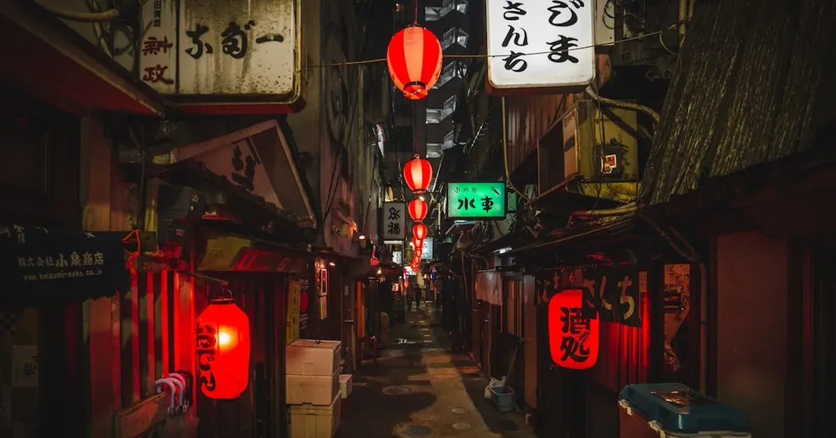 A solo traveler walking down a Tokyo street at dusk with neon signs glowing