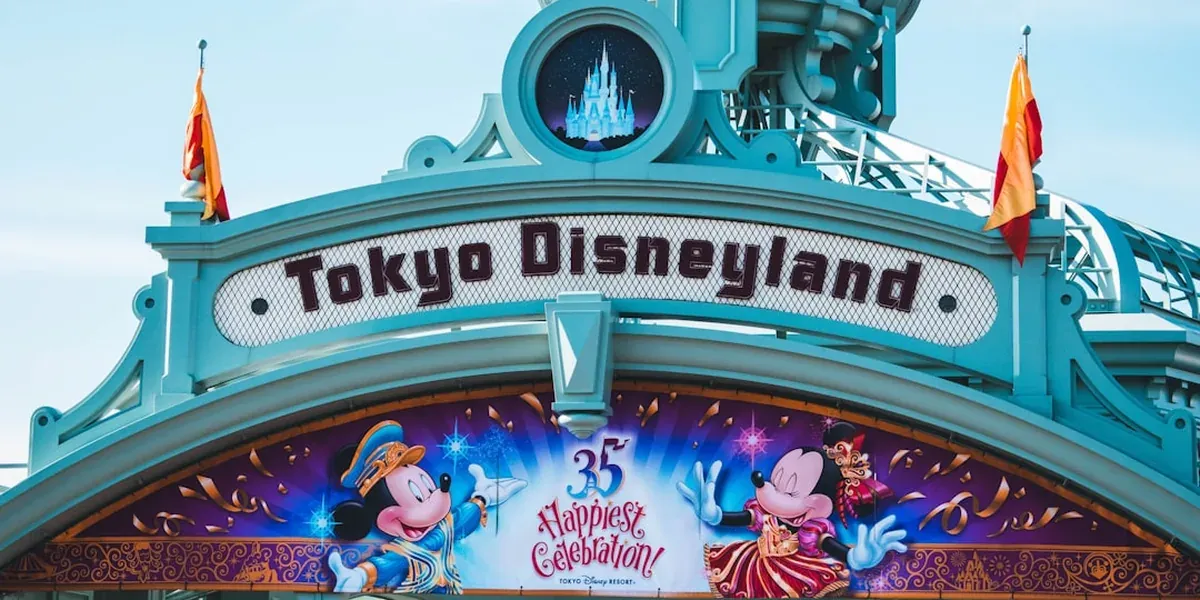 Tokyo Disneyland castle illuminated in pink and blue lights at dusk