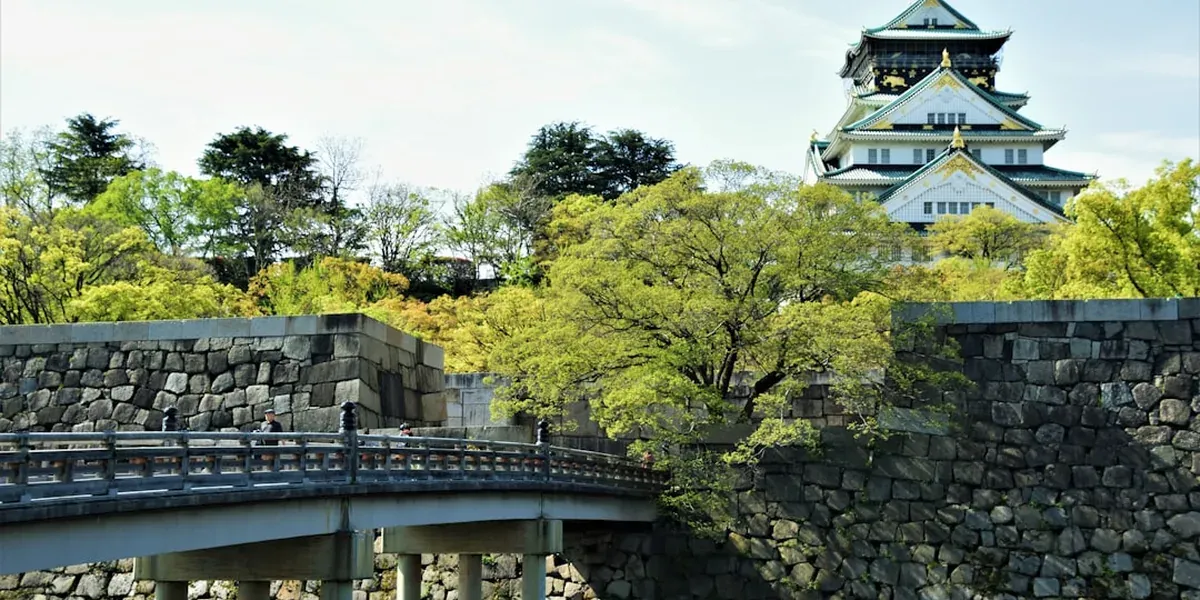Osaka Castle surrounded by park grounds and the historic stone moat on a clear day