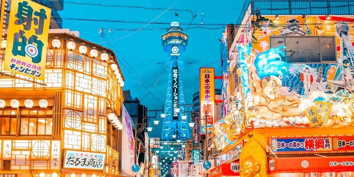 The Tsutenkaku Tower rising above the Shinsekai district in Osaka with retro neon signs at night