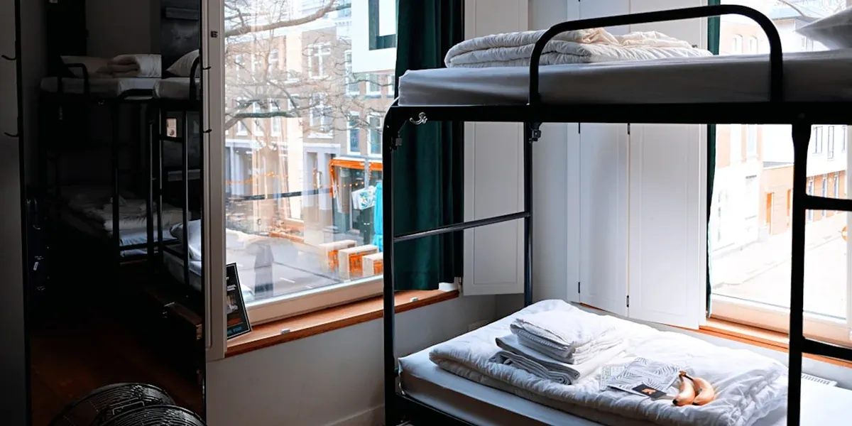 A modern hostel dorm room with bunk beds, lockers, and clean design
