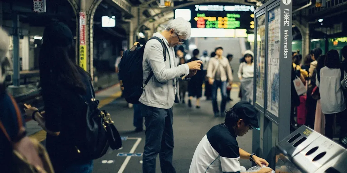 Person checking phone navigation at a busy Japanese train station with multiple exits