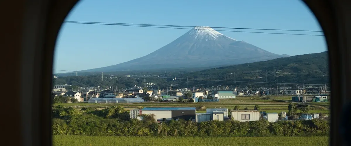 Mount Fuji visible in the distance from a Hakone onsen town with steam and pine trees