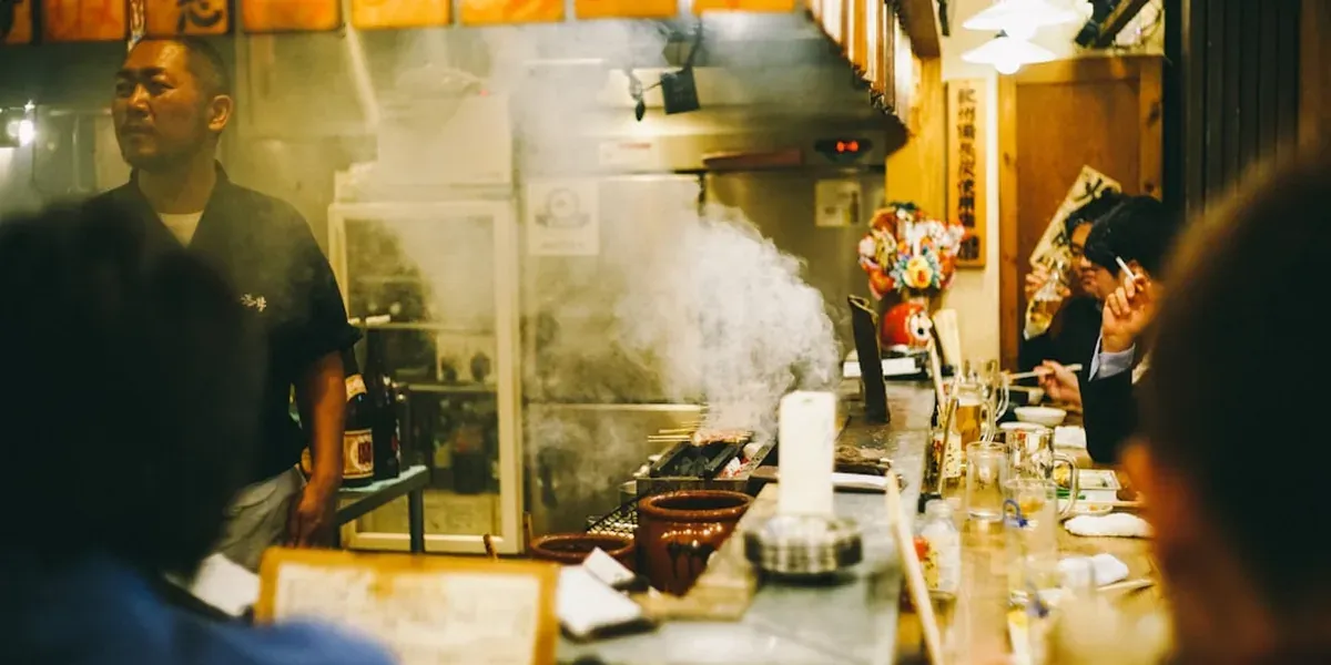Hiroshima-style layered okonomiyaki being cooked on a hot teppan griddle