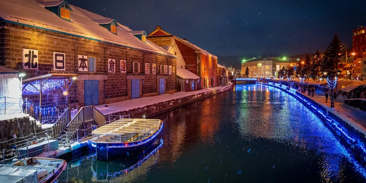 Otaru Canal in Hokkaido at night with snow-covered banks and glowing snow lamps reflecting in the water