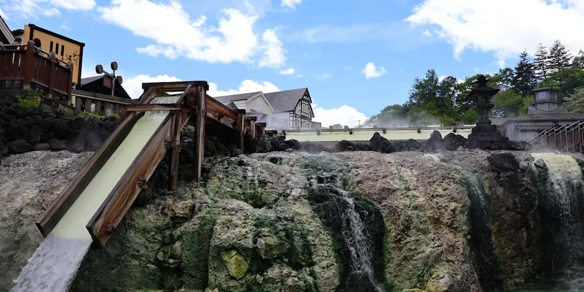 Outdoor rotemburo hot spring onsen in Japan with steam rising and forest surroundings