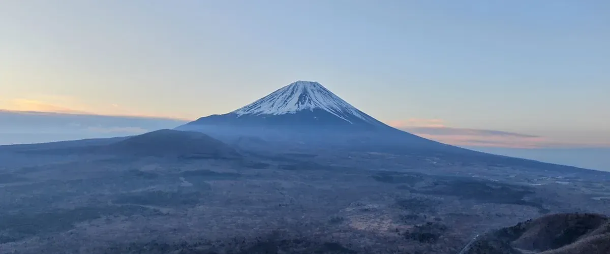 Climbers walking up the rocky trail of Mount Fuji at sunrise during the climbing season