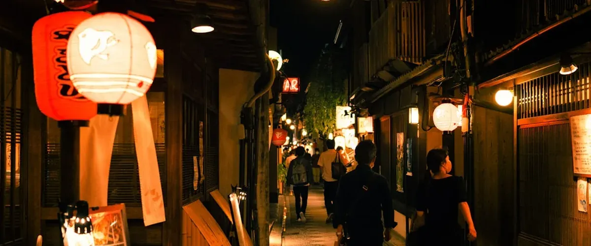 Traditional wooden buildings in Pontocho alley Kyoto at night with red paper lanterns glowing
