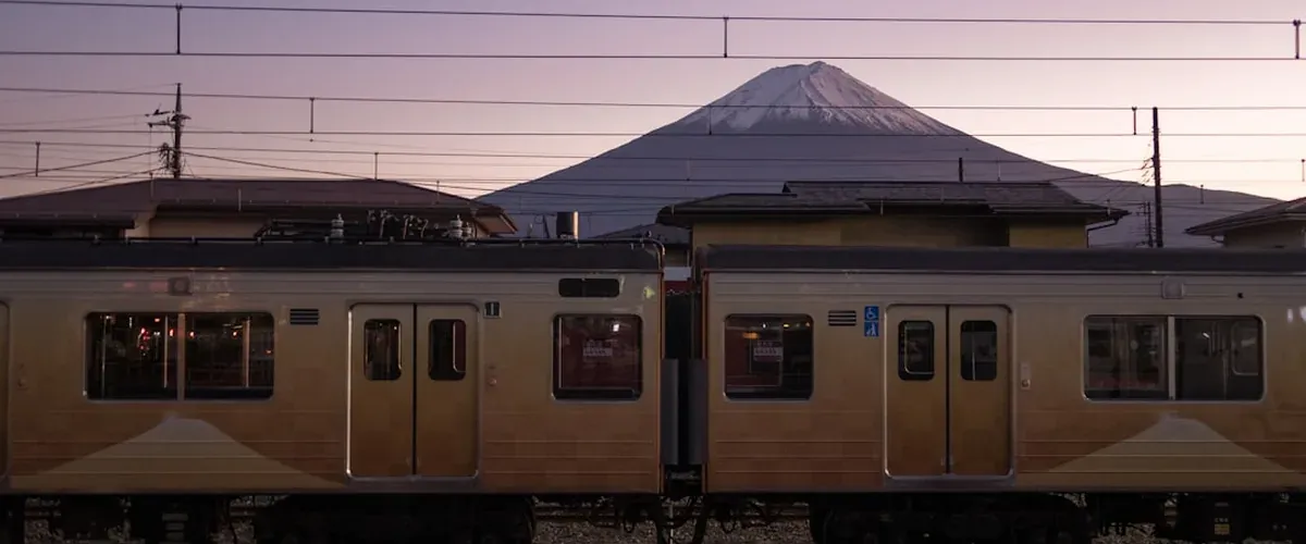 A local Japan train traveling through rural countryside on a sunny day