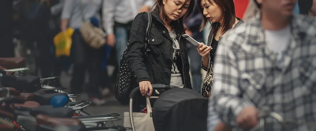 Traveler checking phone while exploring a Japanese street with temples and shops